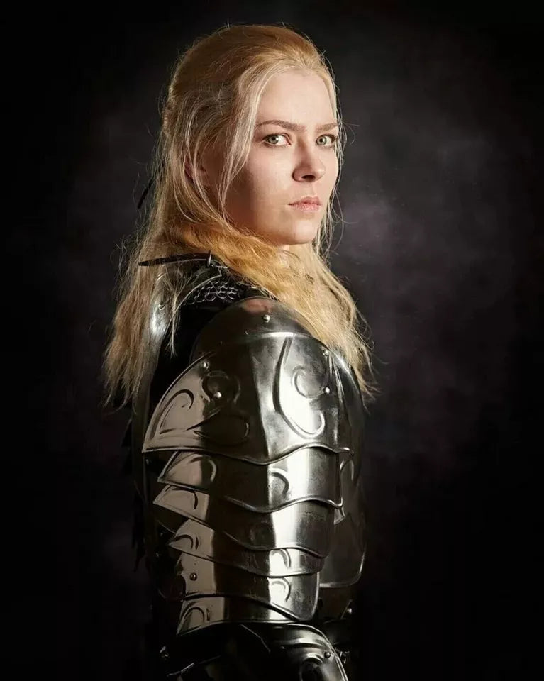 Blonde-haired person in engraved metallic armor, serious expression, dark smoky background.