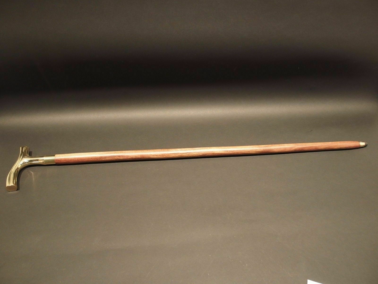 Close-up of the polished brass derby head handle on a Victorian-style wooden walking stick cane, showcasing fine craftsmanship and elegant design.