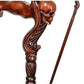 Close-up of the skull-shaped handle on a wooden walking cane, showcasing detailed craftsmanship.